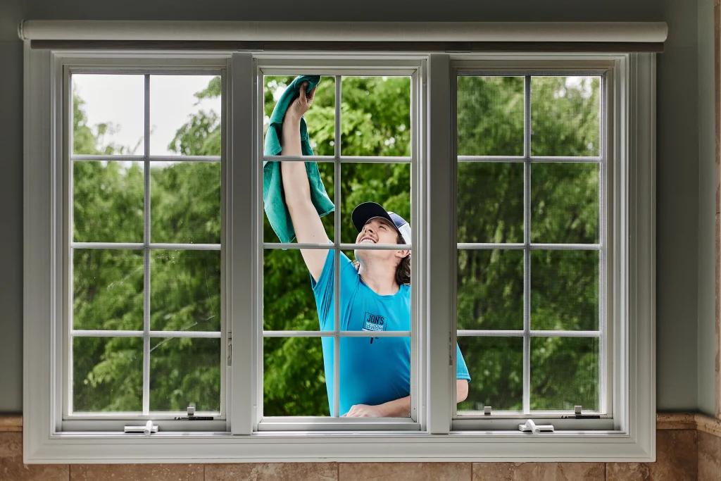 Exterior window cleaning professional using a ladder to wash high residential windows