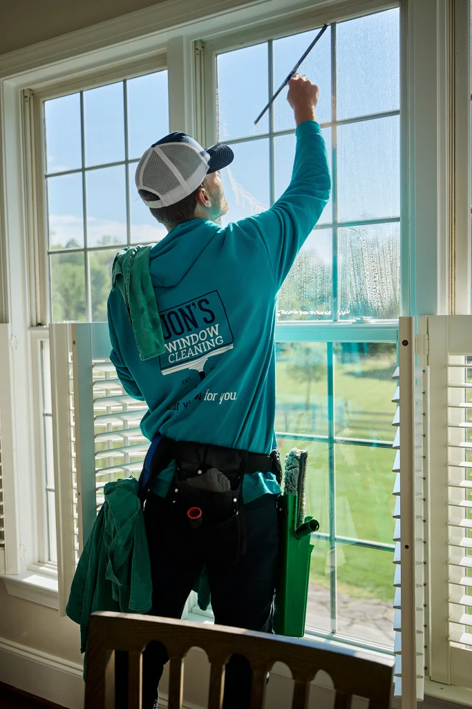 Residential window cleaning crew professionally washing windows around the exterior of a home
