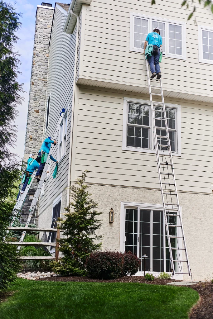 Professional window cleaning team washing exterior windows on a large residential house
