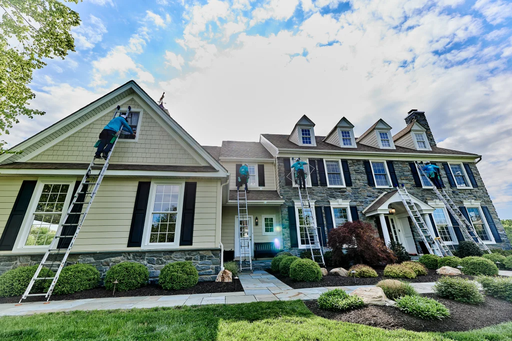 Residential window cleaner using a ladder to reach high exterior house windows