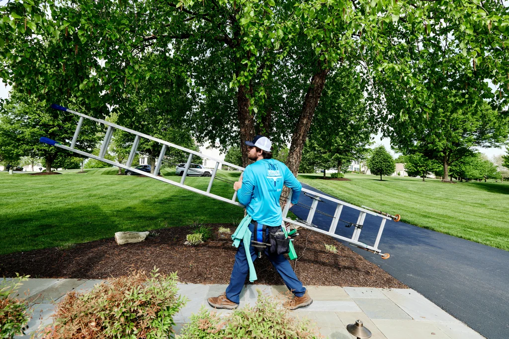 Two-story home window cleaning with professionals reaching upper and lower windows