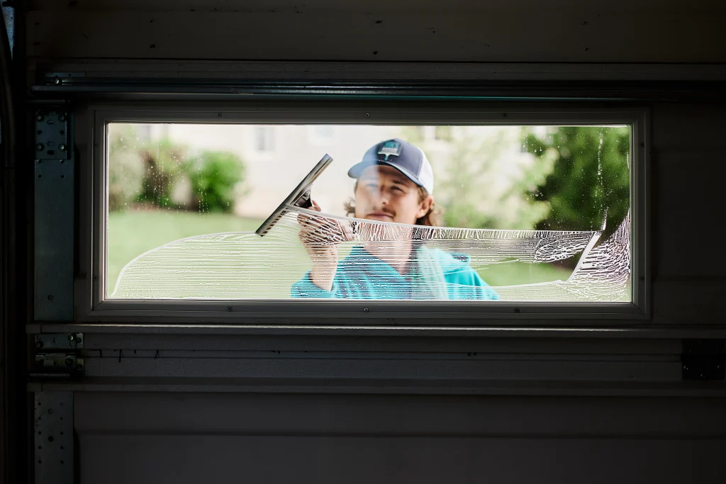 House window cleaning team washing residential windows from multiple ladders
