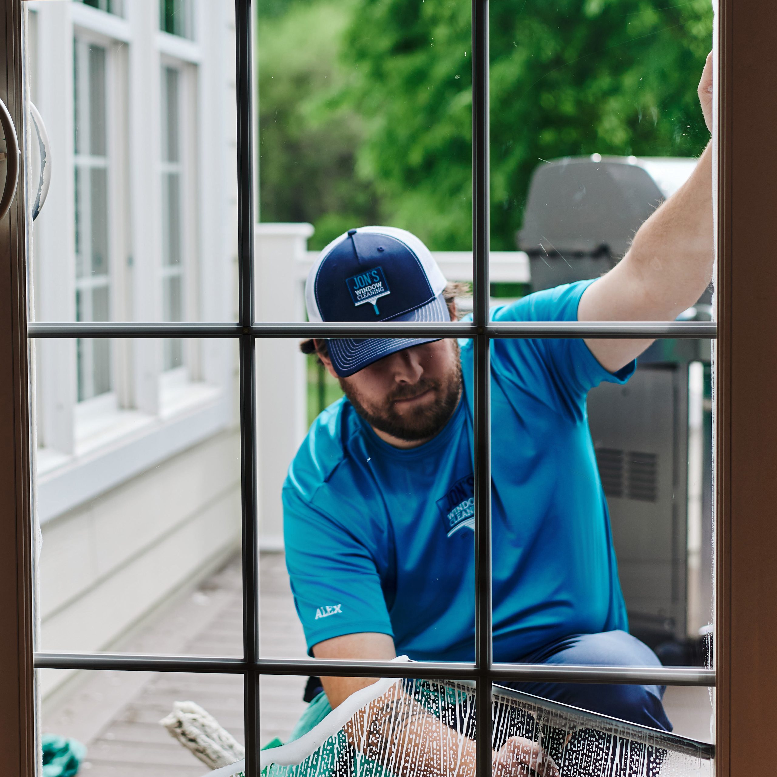 Professional window cleaner cleaning the exterior of a residential sliding glass patio door